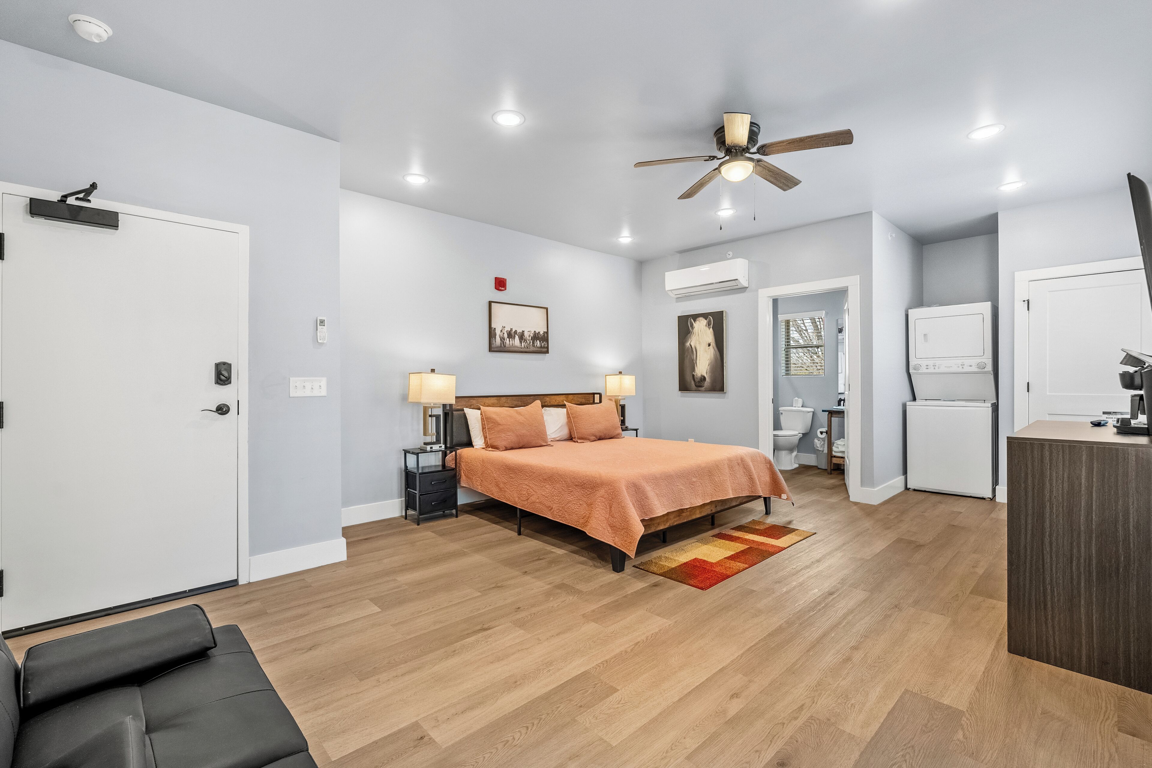 A modern bedroom with a bed, bedside tables, a ceiling fan, and an air conditioning unit.