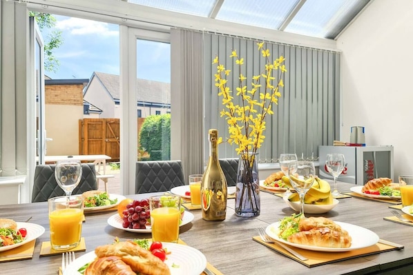 A breakfast setting with a table, breakfast items, and a bottle of champagne.