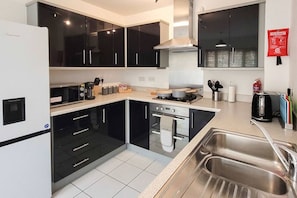 A modern kitchen with black cabinets, a stainless steel sink, and a gas stove.