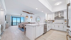 Una cocina moderna con muebles blancos, una isla central y una zona de comedor con vistas.