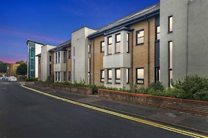 A row of modern buildings with a flat roof, large windows, and a brick facade. - Discover our modern 2-bed apartment in historic Old Town Huntingdon. Features a fun pool/table tennis table, dedicated workspace, and a fully equipped kitchen. Includes a free, pre-registered parking. A unique retreat for work or leisure! (Cambridgeshire)