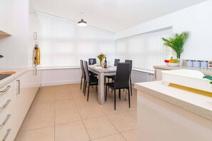 A modern kitchen with white cabinets, a dining table with chairs, a countertop with a sink, and a potted plant. - Discover our modern 2-bed apartment in historic Old Town Huntingdon. Features a fun pool/table tennis table, dedicated workspace, and a fully equipped kitchen. Includes a free, pre-registered parking. A unique retreat for work or leisure! (Cambridgeshire)