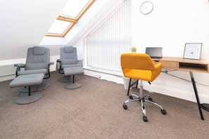 A room with three grey office chairs, a yellow office chair, a desk with a computer, and a skylight.