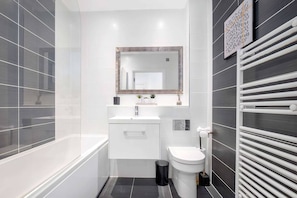 Une salle de bain moderne avec une baignoire, des toilettes et un meuble-lavabo.