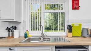A kitchen with a sink, window blinds, a fire blanket, and a washing machine. - The No.7 | Modern 3BR House | Pool Table Pingpong (Brampton)