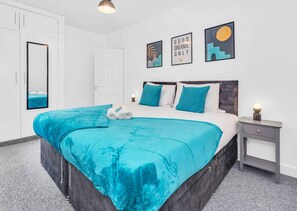 A modern bedroom with a large bed, a bedside table, a wardrobe, and a door.