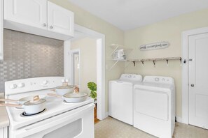 A kitchen with a stove, oven, and a wall-mounted drying rack.