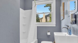 Un baño con una bañera blanca, un inodoro blanco y un lavabo con un espejo encima.