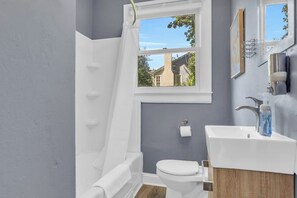 Un baño con una bañera blanca, un inodoro blanco y un lavabo con un espejo encima.