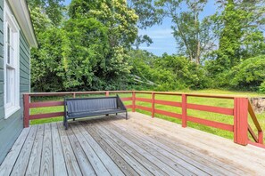 A wooden deck with a bench, surrounded by a red fence and lush greenery. - Cute Bungalow near Downtown, Sleeps 6 (Spartanburg)