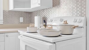 A kitchen with white cabinets, a white stove, and a tiled backsplash.