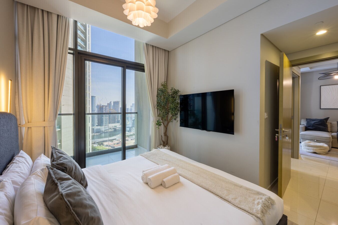 Ein modernes Hotelzimmer mit einem großen Bett, einem an der Wand befestigten Fernseher und einem Balkon mit Blick auf die Stadt.
