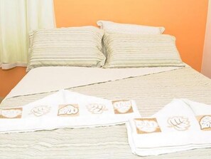 A bed with a striped bedspread and two pillows. - Pousada Morro do Pico (Fernando de Noronha)