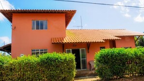 A two-story house with a tiled roof, a small porch, and a door leading to the entrance. - Pousada Morro do Pico (Fernando de Noronha)