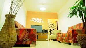 A living room with two sofas, a TV, and a decorative wall piece. - Pousada Morro do Pico (Fernando de Noronha)