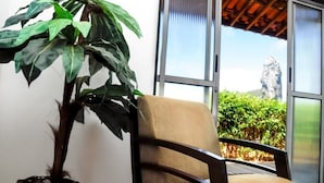 A room with a large window, a chair, and a potted plant. - Pousada Morro do Pico (Fernando de Noronha)