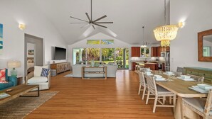 Un vaste espace de vie doté d’un plancher en bois, d’une table à manger dressée pour six personnes et d’une cuisine à l’arrière-plan.
