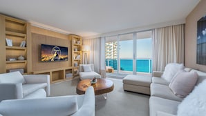 Ein modernes Hotelzimmer mit großem Balkon, Flachbildfernseher, Holztisch und Bücherregal.