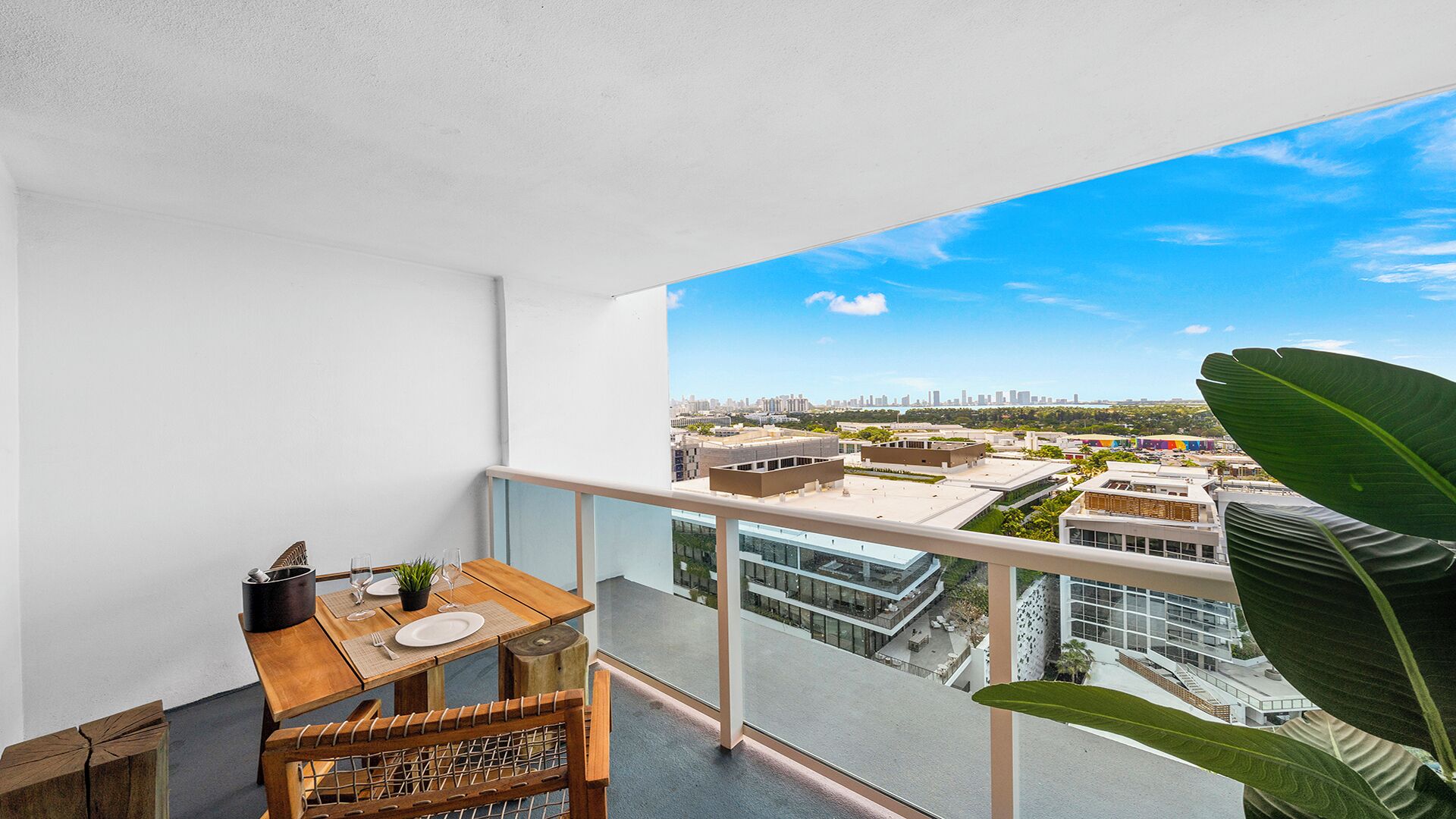 Ein Balkon mit Esstisch, Stühlen und Blick auf eine Stadtansicht.
