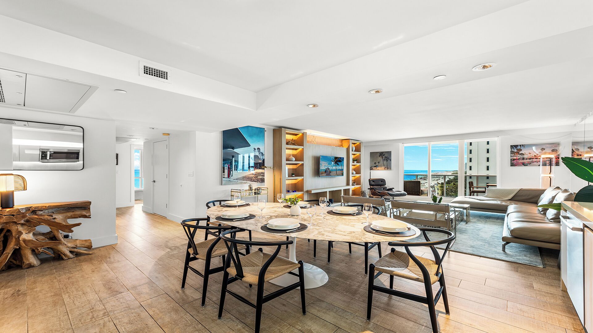 A spacious living area with a large dining table, comfortable seating, and a view of the ocean.