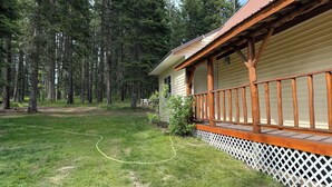 Una cabaña con terraza de madera y valla de celosía blanca.