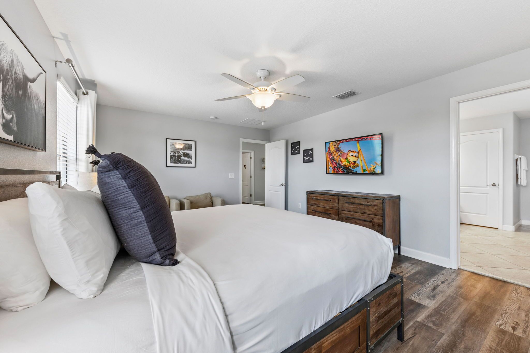 A bedroom with a large bed, a ceiling fan, and a wooden dresser.