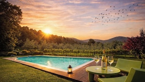 A pool with a wooden deck, surrounded by greenery and hills. - Il Palazzaccio | Nature, Pool & Relaxation in Lucca (Lucca)