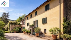 A traditional building with a gravel driveway, potted plants, and a staircase leading to the entrance. - Il Palazzaccio | Nature, Pool & Relaxation in Lucca (Lucca)