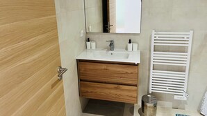 Une salle de bain moderne avec un meuble-lavabo en bois, un lavabo blanc, un miroir et un porte-serviettes blanc.