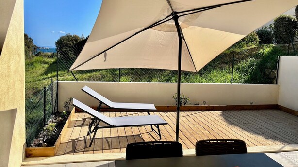 Une terrasse avec une table, des chaises et un grand parasol.