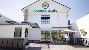 A white building with a green logo and the name "Pondok Audy" on the facade. - Pondok Audy (Sinduadi)