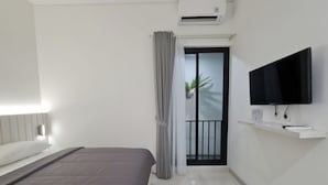 A modern hotel room with a bed, a TV mounted on the wall, and an air conditioning unit above the door. - Pondok Audy (Sinduadi)