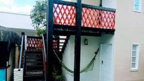 A covered outdoor area with a staircase, a hammock, and a door. - Pousada Água Marinha (Porto Seguro)