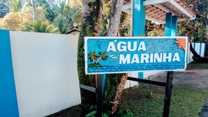 A sign for 'ÁGUA MARINHA' with palm trees and a blue background. - Pousada Água Marinha (Porto Seguro)