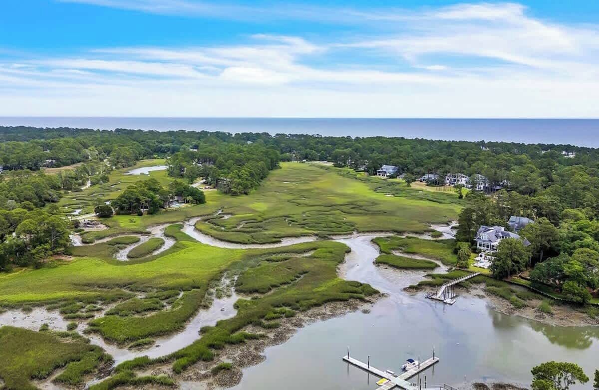 Un paisaje costero con un río, zonas pantanosas y un muelle.