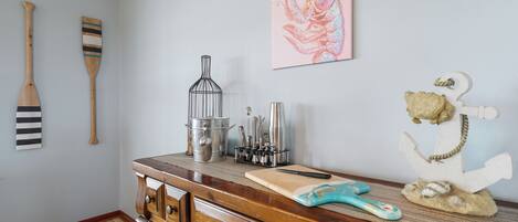 A kitchen with wooden cabinets, a cutting board, a knife, a metal pot, and a lobster painting on the wall.