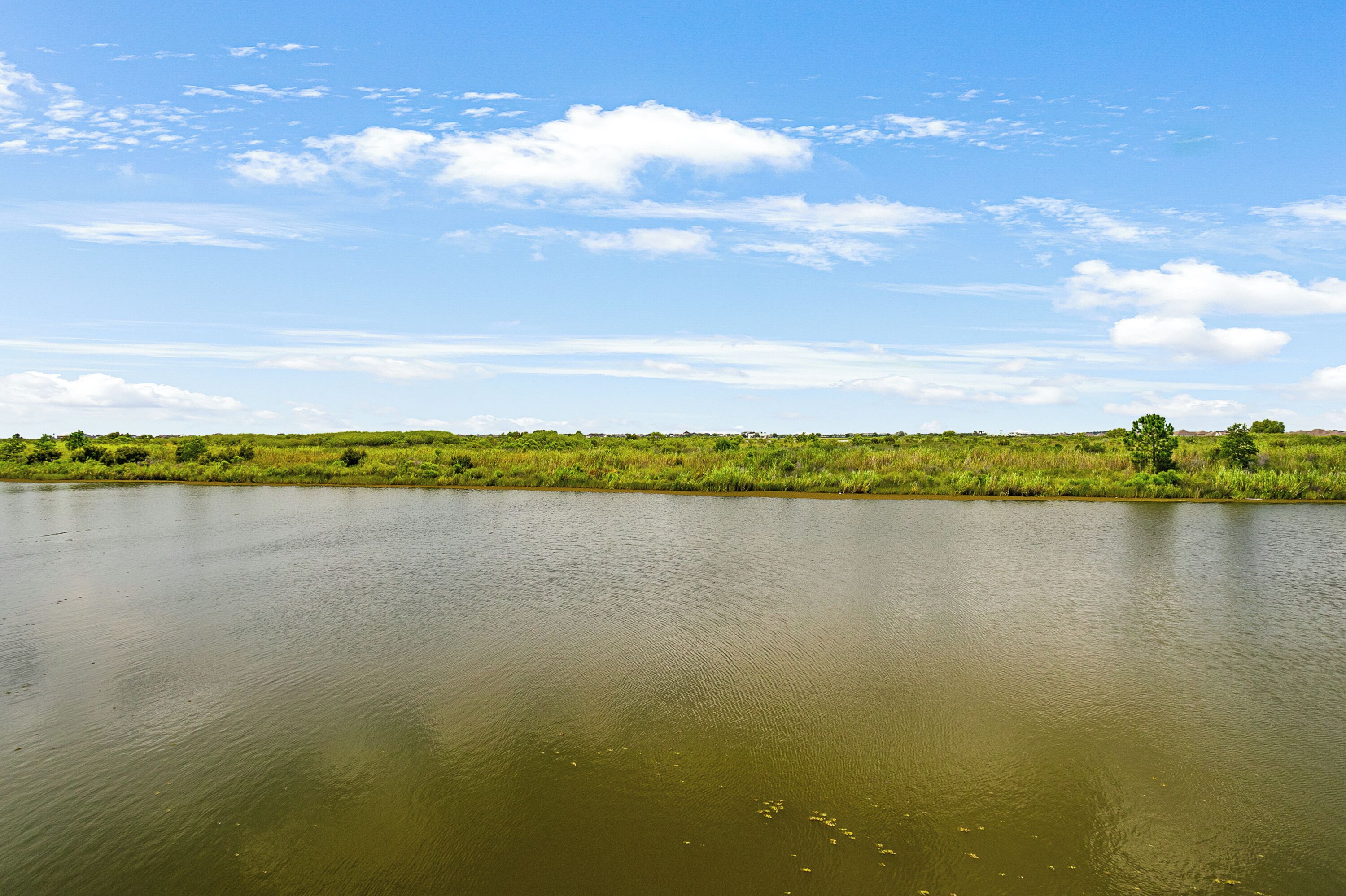 A calm lake with a grassy shoreline and a clear sky.