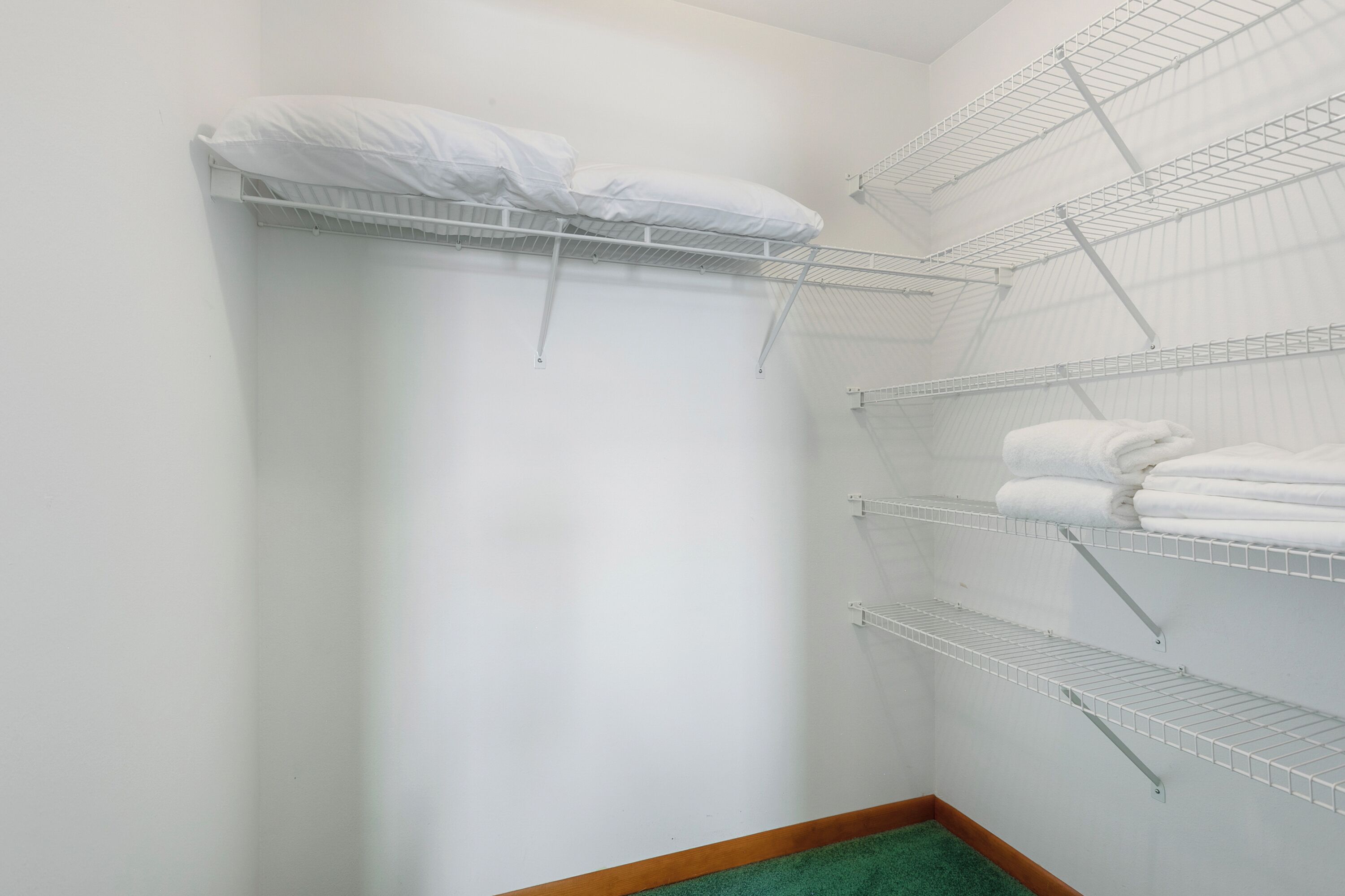 A small, white-walled room with a built-in shelf unit holding folded towels.