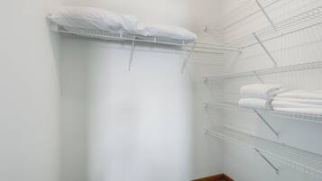 A small, white-walled room with a built-in shelf unit holding folded towels.