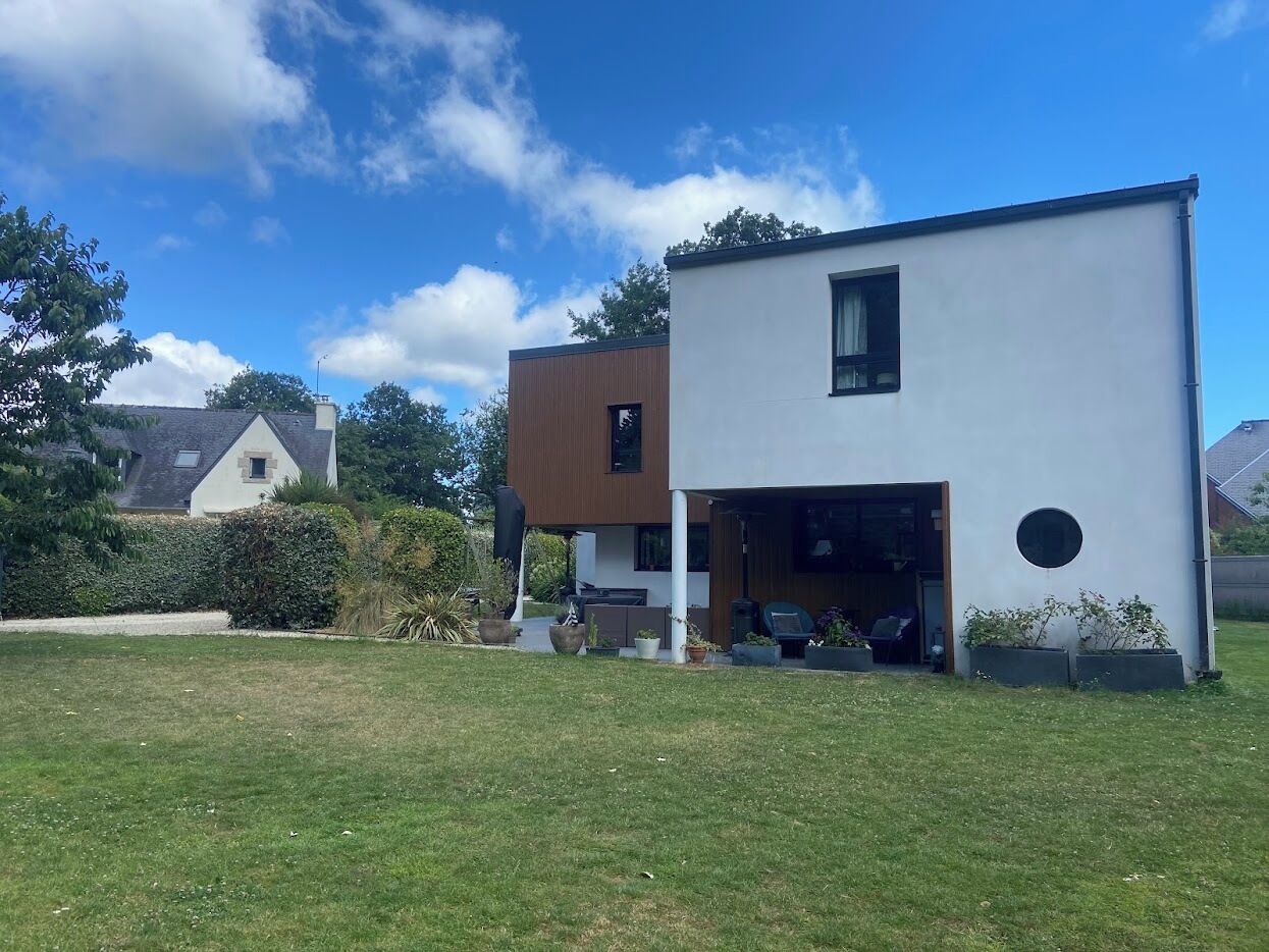 A modern two-story house with a white exterior and a brown roof.