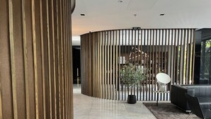 A modern interior with a curved wooden partition, a black leather sofa, and a potted plant.