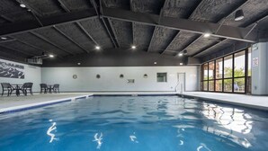 Ein Innenpool mit Betondecke, Wandgemälde und Blick ins Freie.