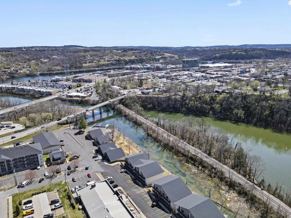 An aerial view of a town with a river, a bridge, and a parking lot with buildings.