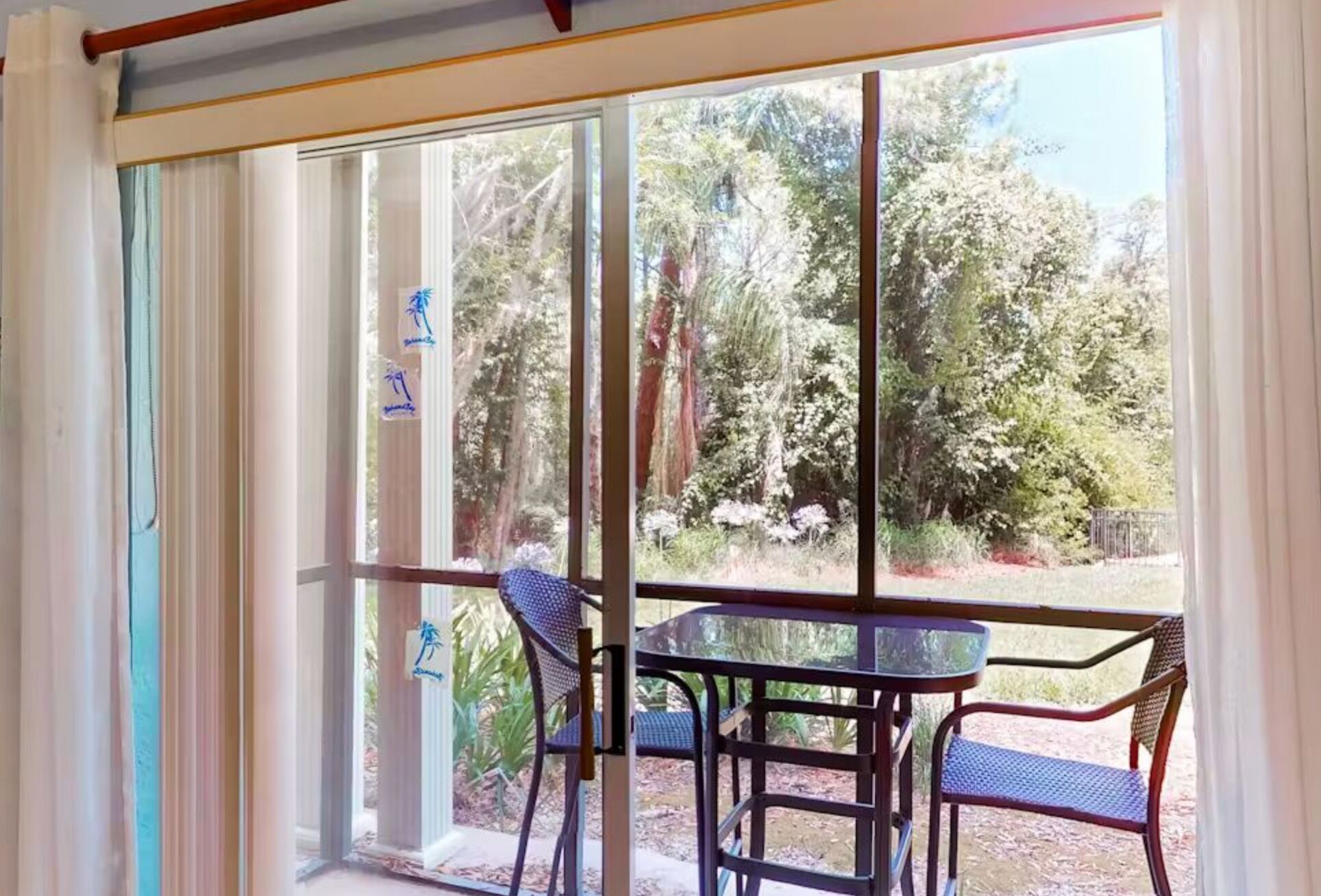 Une pièce dotée d’une porte-fenêtre coulissante donnant sur une terrasse avec une table et des chaises.