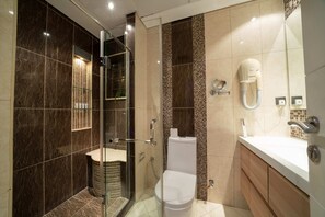 A modern bathroom with a glass-enclosed shower, a toilet, and a sink with a mirror.