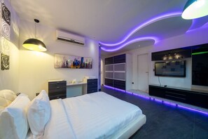 A modern bedroom with a bed, bedside tables, a desk, and a wardrobe.