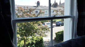 A window with a view of a residential street, including houses and parked cars. - 1840's Converted Railway Cottage (Swindon)