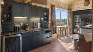 A modern kitchen with dark cabinets, a herringbone backsplash, and a wooden ceiling. - Elk Lodge Cabin for 4! (Branson)