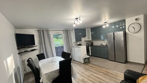 A compact living space with a dining area, kitchenette, and a TV mounted on the wall. - Bright and Spacious 3-Bedroom Apartment - Direct Access to Central Paris (Choisy-le-Roi)