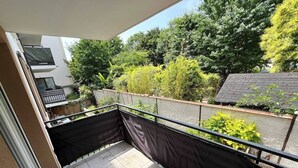 A balcony with a view of a garden and a building in the background. - Bright and Spacious 3-Bedroom Apartment - Direct Access to Central Paris (Choisy-le-Roi)